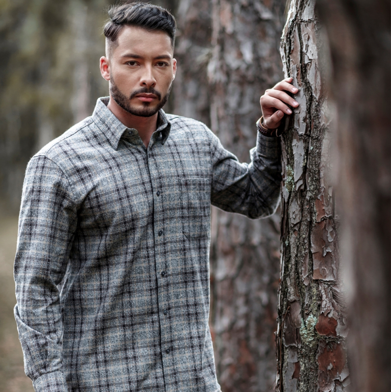 Homem com camisa azul xadrez. Seu cabelo é azul escuro, com fios