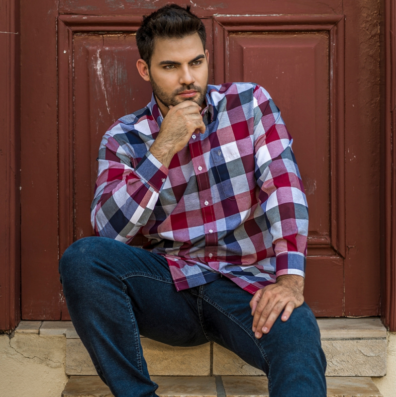 Homem com camisa azul xadrez. Seu cabelo é azul escuro, com fios